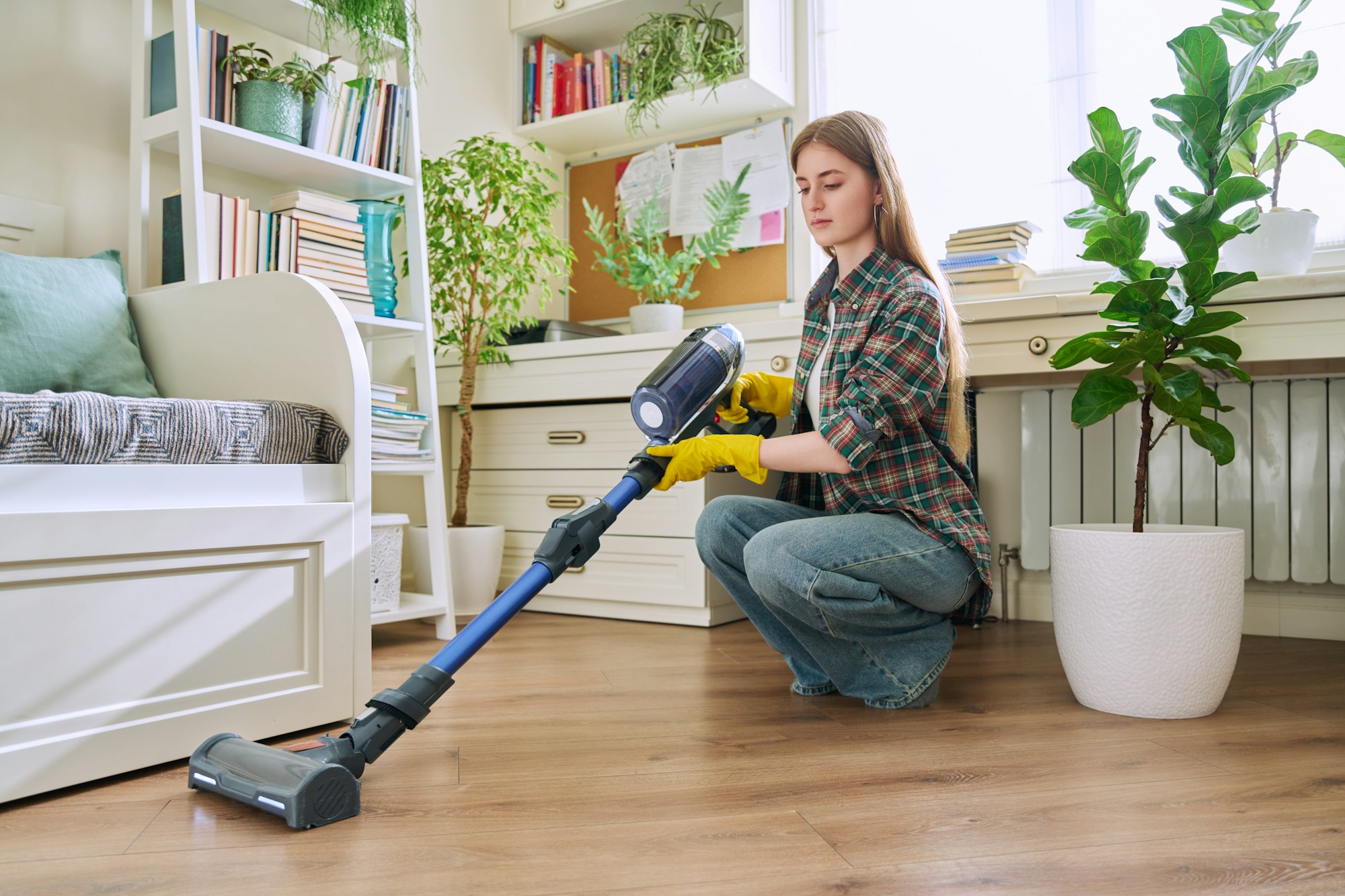 Young teenage girl vacuuming house, cleaning room